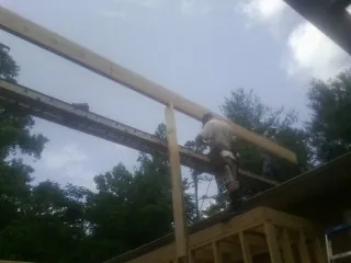 Carpenter setting a ridge beam over a new addition frame — Ice Dam Removal by Roofing Brothers in Artesia