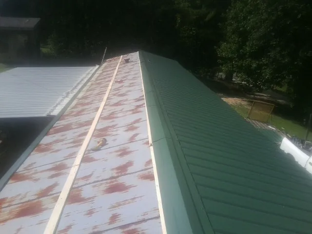 Old rusted panels beside newly installed green metal roofing — Wind Damage Roof Repair by Roofing Brothers in Artesia