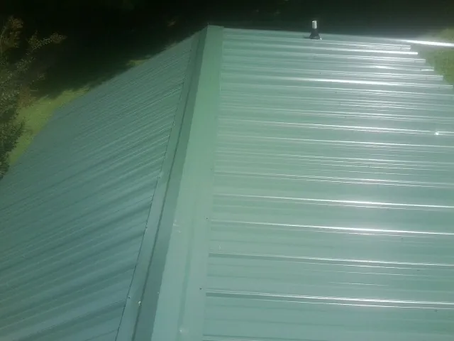 New green metal panels meeting at the ridge of a roof — Flat Roof Repair work by our crew in Artesia