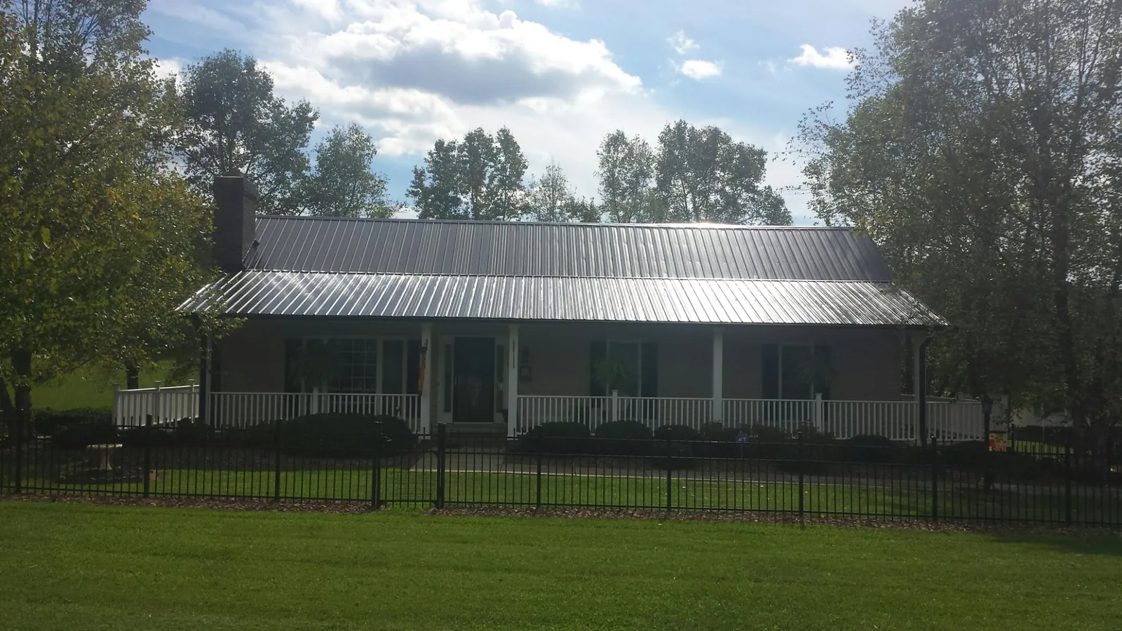Gray metal roof on a brick ranch with a full width front porch — Gutter Guard Installation work by our crew in Artesia