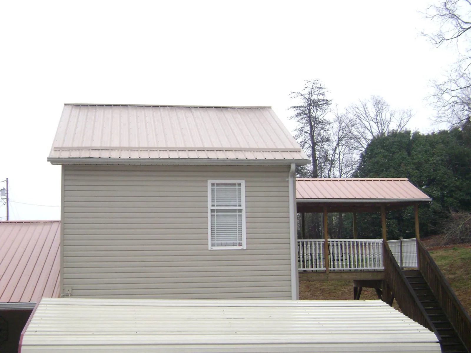 Tan metal roofs on a two story addition and attached porch, from a Roof Replacement job in Artesia
